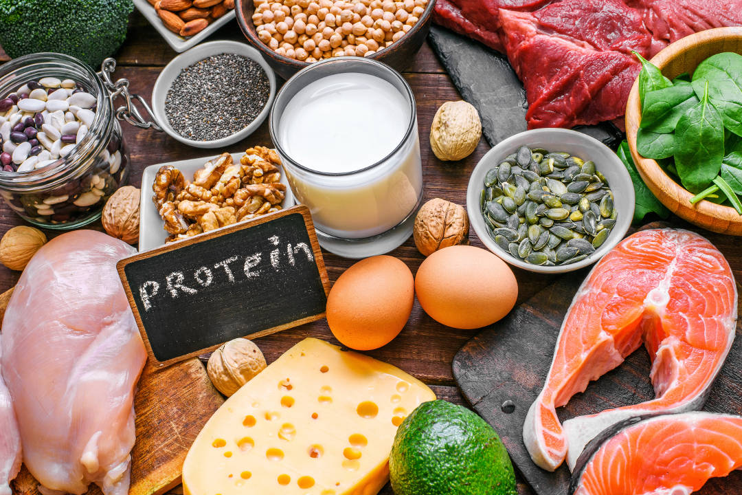 Die richtige Auswahl an Lebensmittel, um gesund zuzunehmen Tisch mit proteinreichen Lebensmitteln, Glas Milch und Tafel mit Aufschrift: Protein