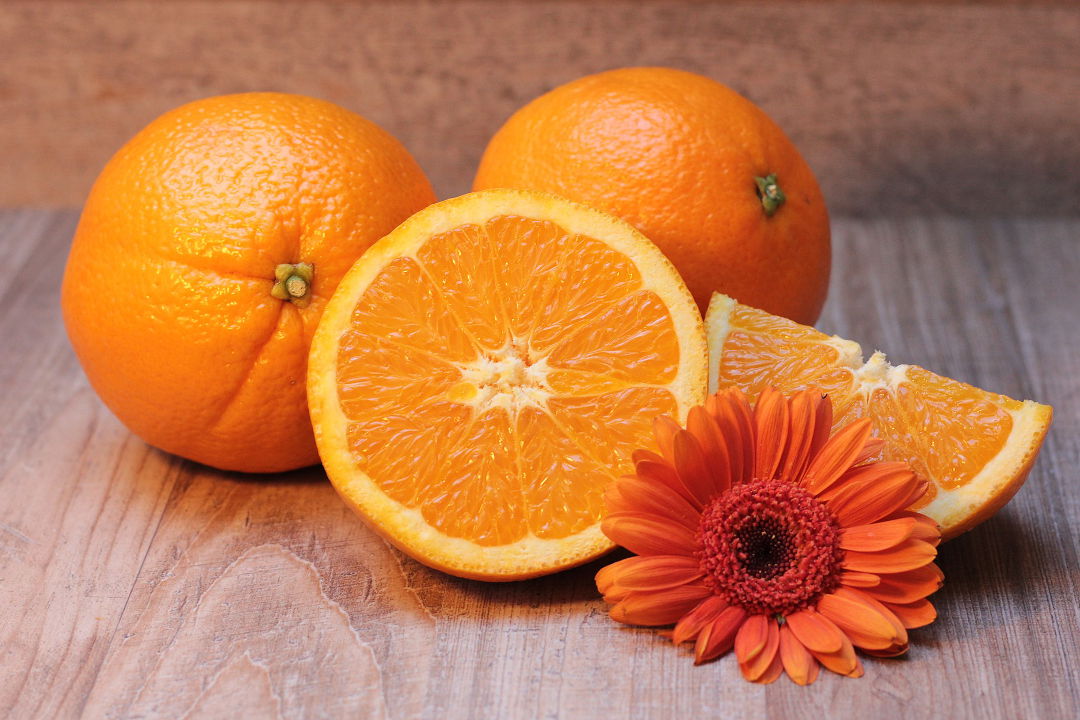 Eine aufgeschnittene und zwei ganze Orangen auf dem Tisch